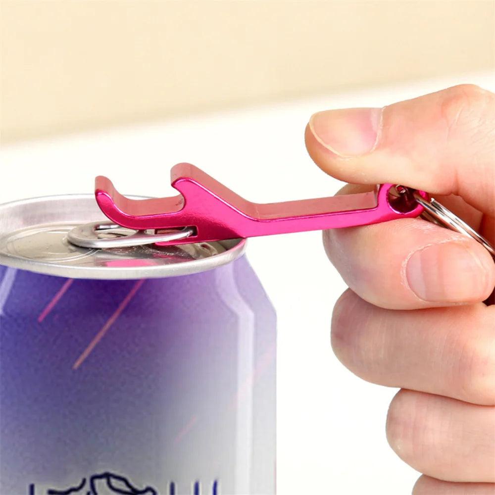 A hand using a pink multifunctional aluminum alloy bottle opener to open a canned beverage.