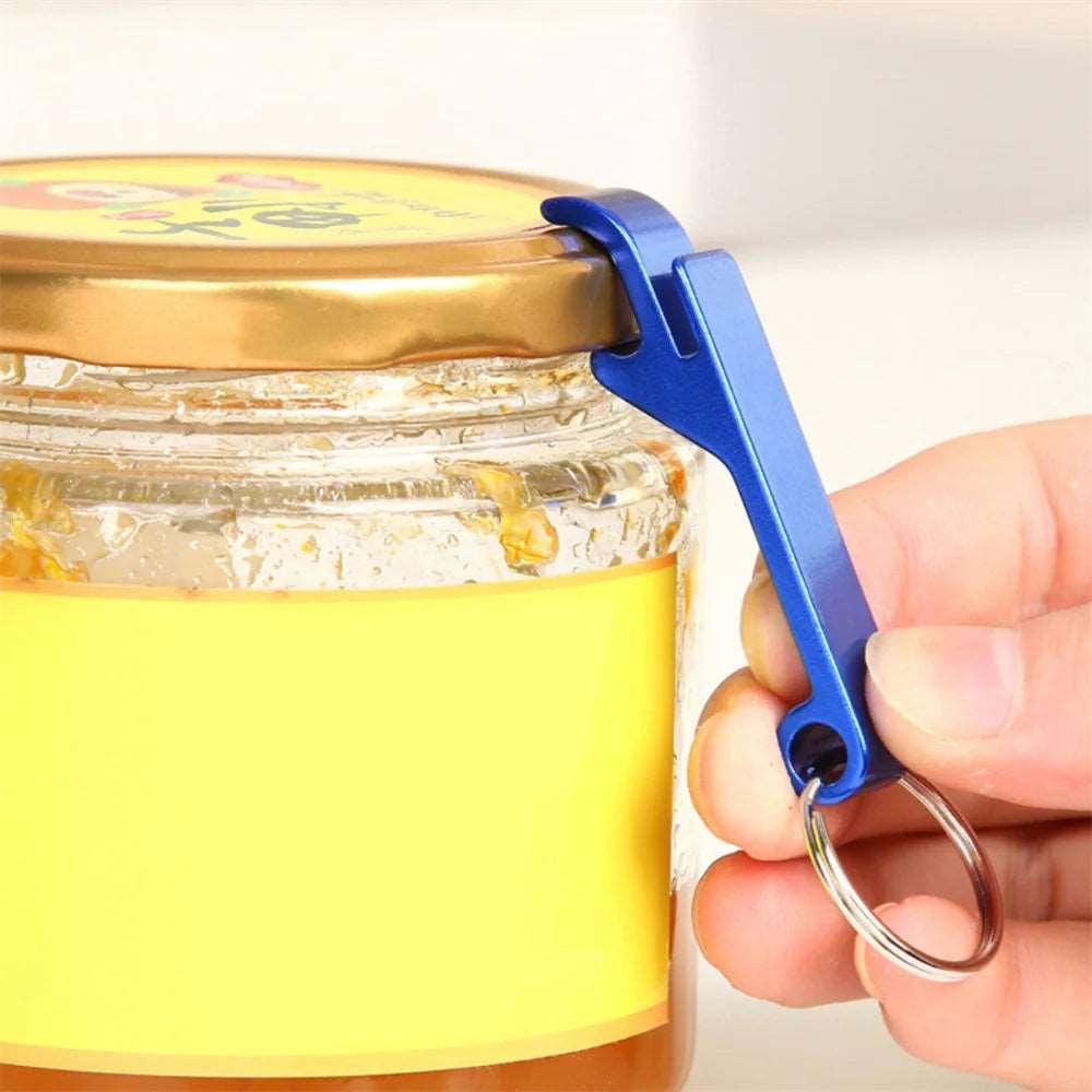 Hand using a blue multifunctional aluminum alloy bottle opener to lift the lid of a jar.