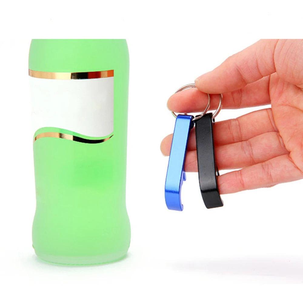 Hand holding two aluminum alloy bottle openers, one blue and one black, alongside a green bottle.