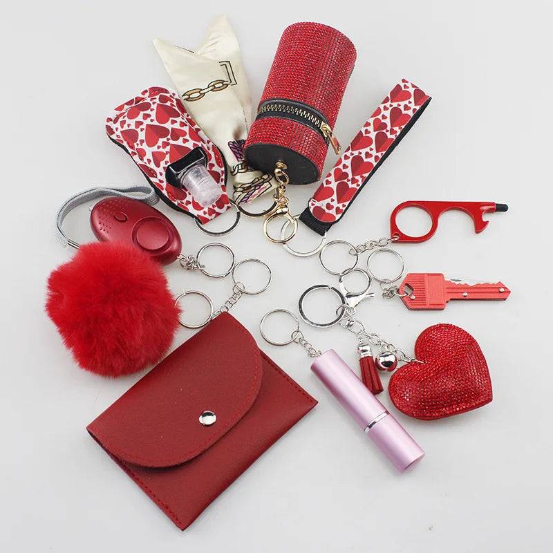 SafetyKey set including a personal alarm, card holder, wristband, lipstick holder, perfume bottle, organizer bag, fluffy pompom, and whistle, all in red and heart-themed designs