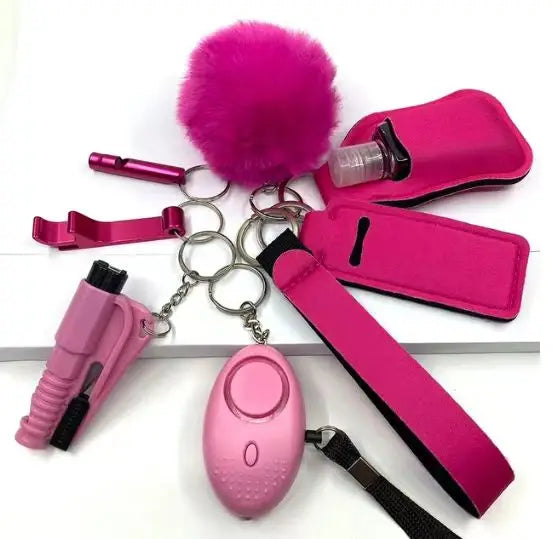 8-delige SafetyKey-set met persoonlijk alarm, LED-lampje, fluitje, flessenhoes, lippenstiftzakjes, flesopener, deurartefact, pompon-bal en polsbandje in roze.