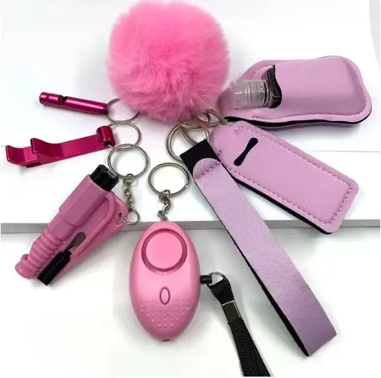 "Set of eight personal safety items including a pink alarm with LED light, whistle, bottle sleeve, two lipstick cases, bottle opener, door opener, fluffy pompom, and wrist strap."