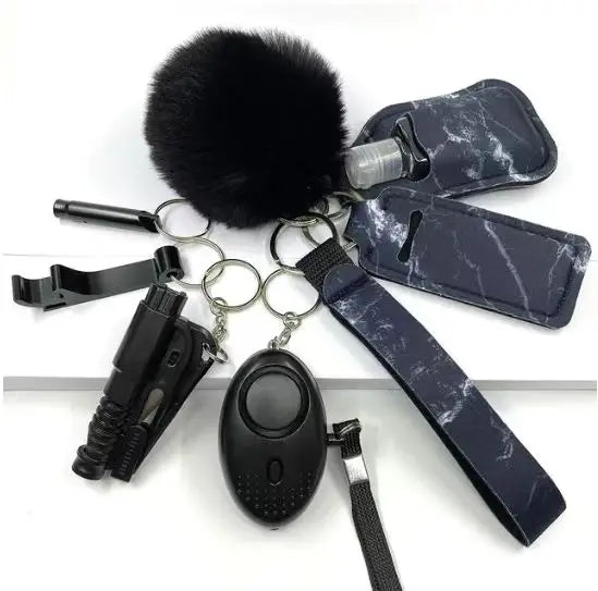 Eight-piece SafetyKey set featuring a personal alarm with LED light, whistle, bottle cover, two lipstick cases, bottle opener, no-touch door opener, pom pom ball, and wrist strap, displayed on a white background.