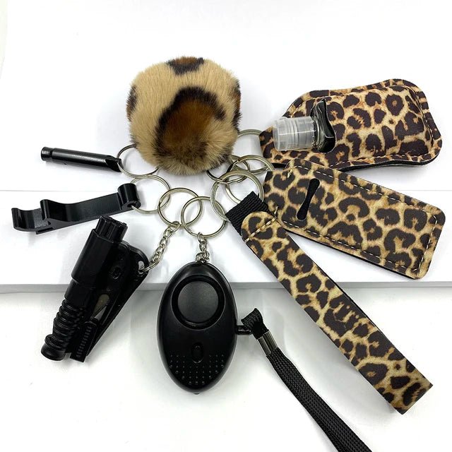 A set of eight self-defense key items featuring leopard print accessories, including a personal alarm, pompom, and sanitizer holder, designed for women's safety and made of high-quality brass material.