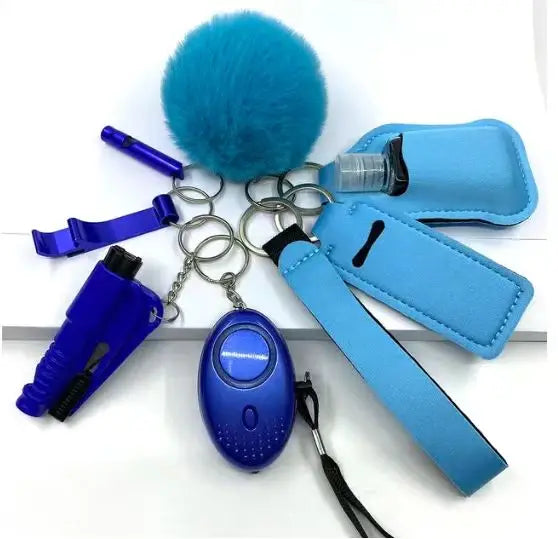 A set of eight blue personal safety accessories including an alarm with LED light, whistle, bottle cover, two lipstick pouches, bottle opener, no-touch door opener, fluffy pompom, and wrist strap.