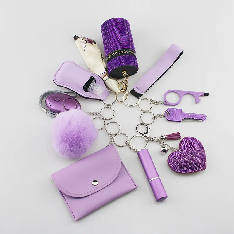 "SafetyKey set" featuring a purple personal alarm, cardholder, wristband, lipstick holder, perfume bottles, organizer bag, fluffy pom-pom, whistle, all attached to a keychain